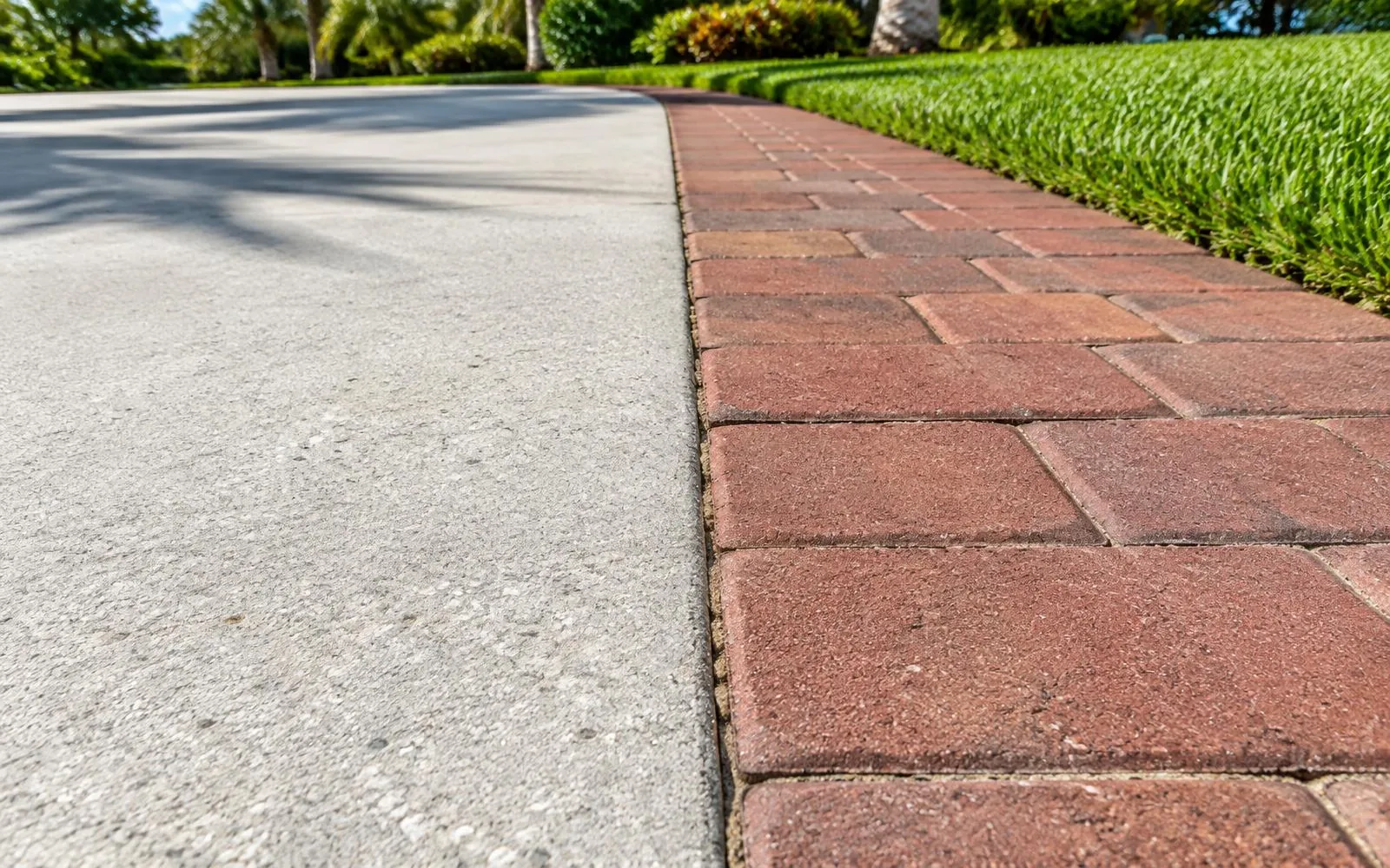 Close-up comparison of concrete and red paver driveway surfaces in Pembroke Pines