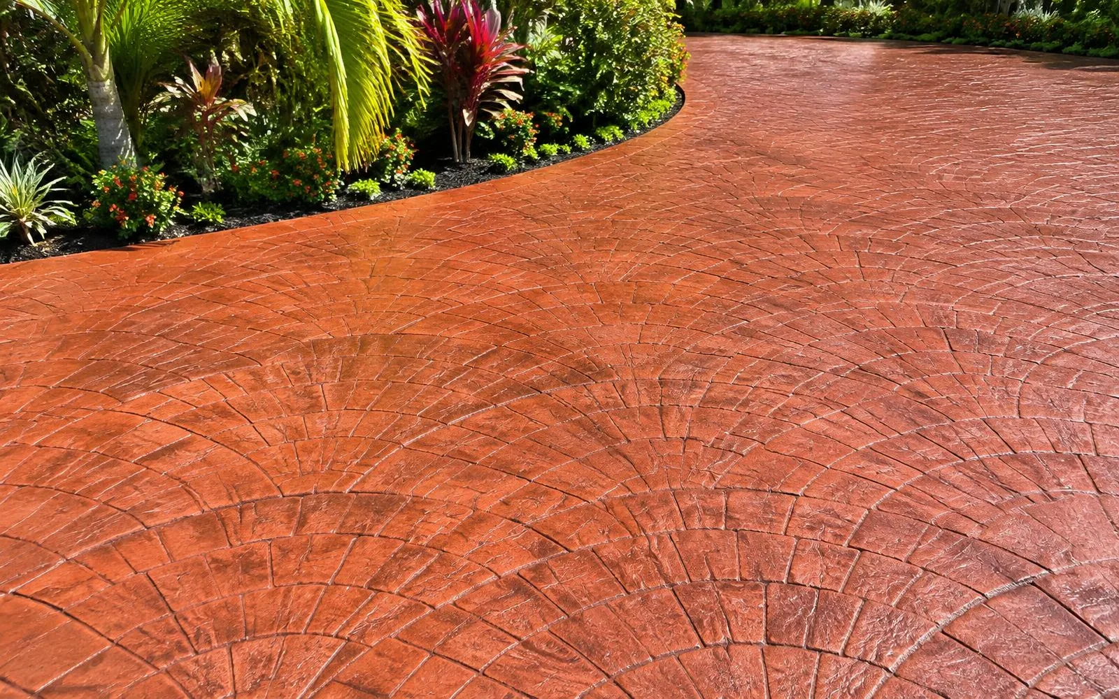 Terracotta fan-pattern stamped concrete beside lush tropical landscaping in Pembroke Pines